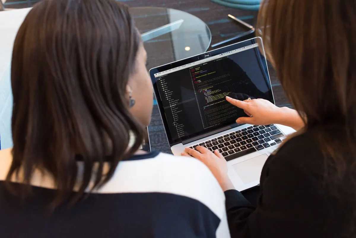 Desarrolladoras revisando código de un sitio web en un portátil